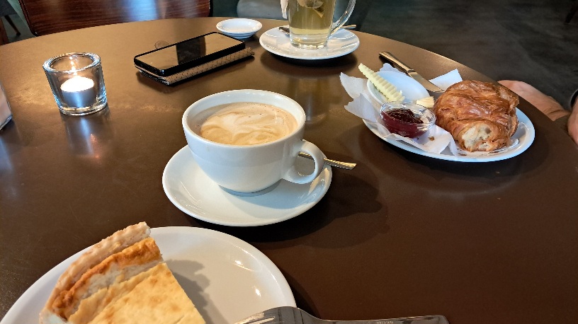 Ein gedeckter Tisch mit Kaffee,
 Kuchen,
 Croissant und Tee.